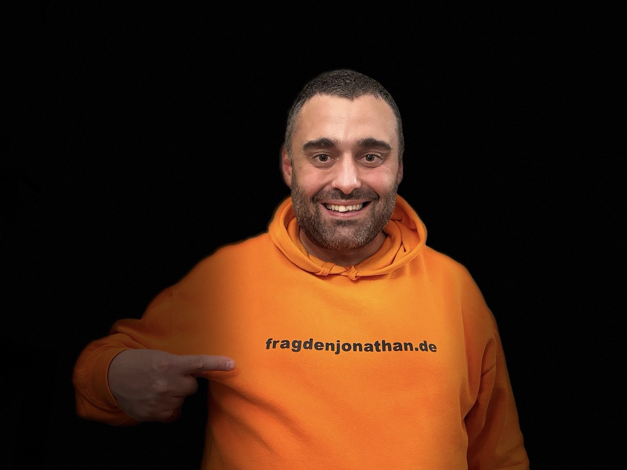 Profilbild von Jonathan Kühnle in einem orangefarbenen Hoodie mit der Aufschrift fragdenjonathan.de